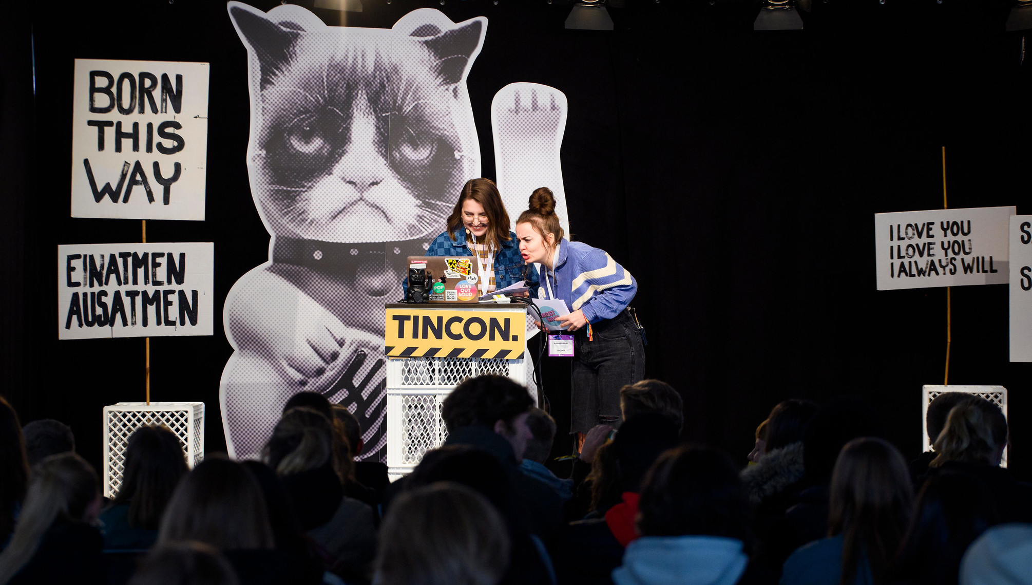 Zwei junge Frauen stehen auf der Bühne der TINCON und sprechen vor Publikum. 